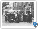 1934, Groepje dames onder leiding van een pastoor poseert voor de St. Rosaliakerk voordat ze een uitstapje gaan maken